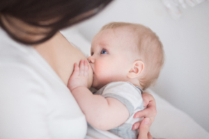 mother breast feeding and hugging baby