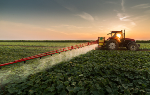 Tractor spraying pesticides on vegetable field with sprayer at spring