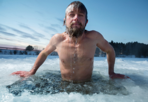 Young man bathing in the ice hole. Focus on hands